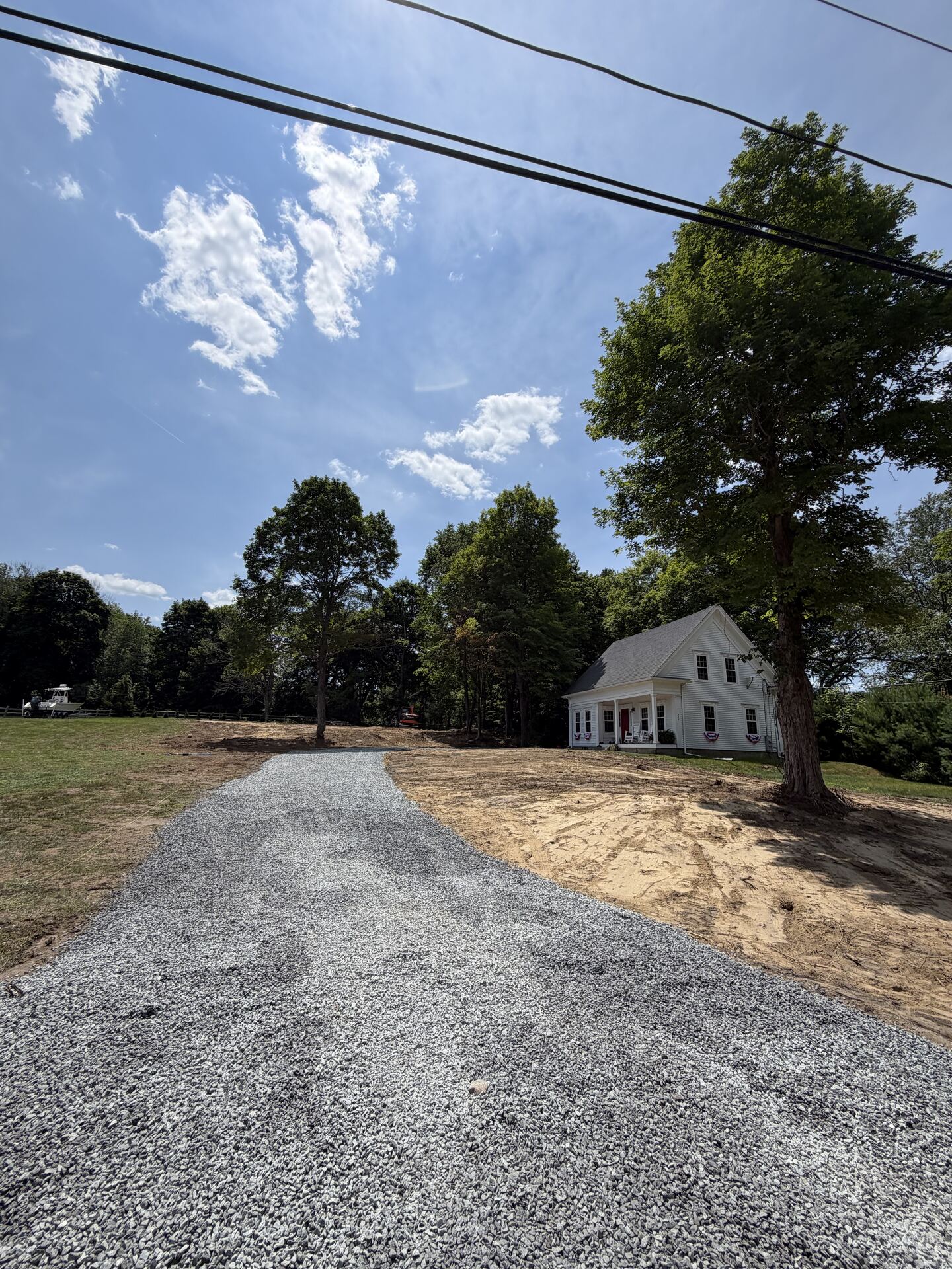 New gravel driveway leading to a farmhouse-style home