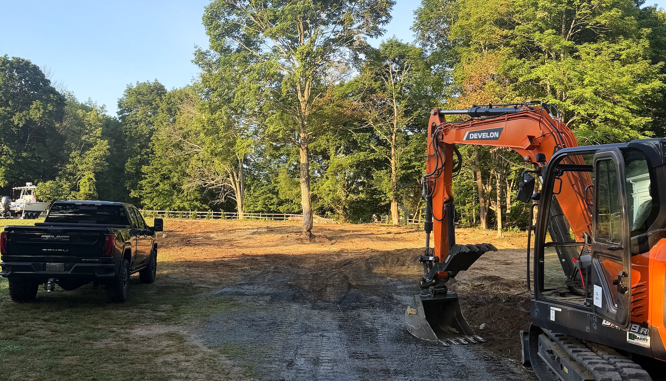 Excavator working a cleared lot at sunrise in Duxbury, MA