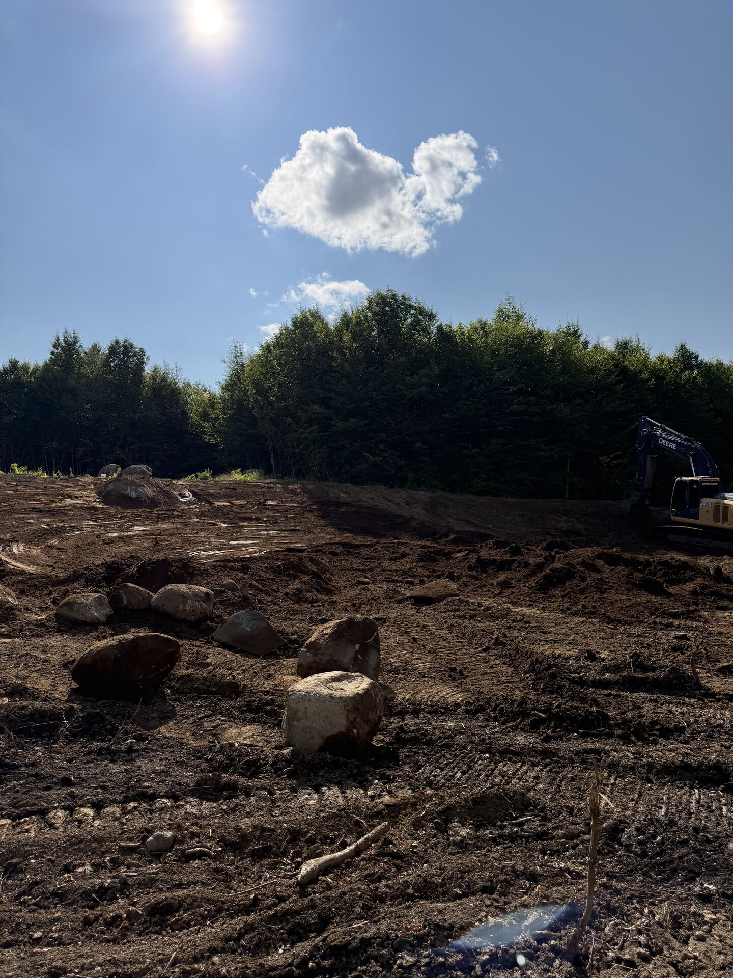 Rough-graded lot with fieldstone staged for removal